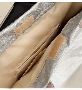 Detail of silver snake-textured tote bag with velcro closure and internal zipper pocket
