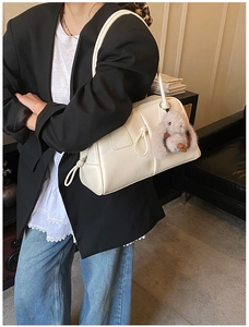 Detail of cream Boston bag featuring drawstring knot and a plush bunny charm on shoulder