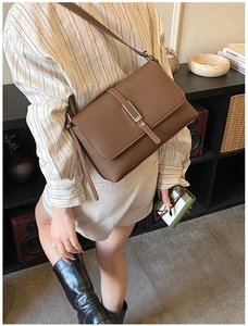 Detail of dark brown lychee leather bag with elegant metal buckle and adjustable strap