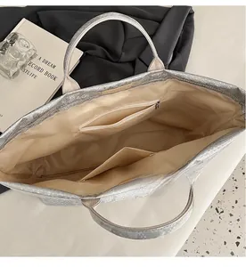 Detail view of large silver tote bag interior featuring zipper pocket and lining