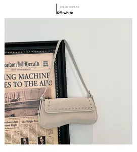 Detail of cream white PU shoulder bag featuring silver rivets and curved bottom edge