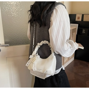 Ruched handle shoulder bag with pearl bow charm shown in a stylish lifestyle setting