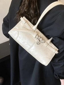 Sac baguette en cuir blanc crème avec lanières porté par un mannequin en blazer noir