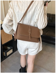 Detailed back view of a brown leather shoulder bag shown on a model for scale and style