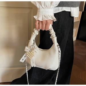 Detail of pleated handle and heart pearl charm on cream white shoulder bag