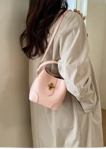 Detail of pink lychee leather bucket bag with gold lock buckle and crossbody strap