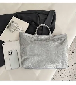 Silver snakeskin tote bag with PVC outer layer showing large capacity with a tablet