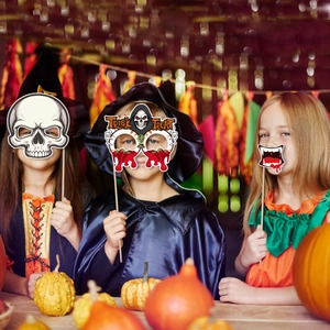 Kids wearing Halloween photo booth props with skull masks and pumpkin decorations
