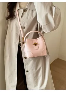 Detailed close-up of pink bucket bag featuring litchi grain texture and gold twist lock