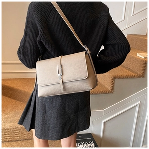 Detail of grey lychee leather texture and silver metallic buckle on a shoulder bag