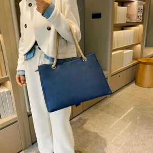 Detail of navy blue woven tote bag with braided rope handle and metal eyelets
