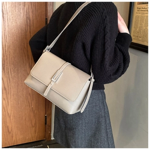 Detailed view of the taupe lychee texture leather shoulder bag worn by a model