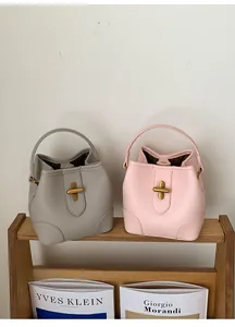 Detailed view of bucket bags in pebble leather with gold cross-shaped metal closures