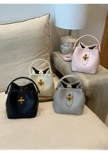 Mini bucket bags in four colors with lychee texture and gold cross locks on a side table