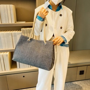 Detail of woven tote bag with rope handles styled with a minimalist beige blazer