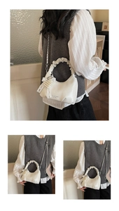 Close-up of white pleated handbag with pearl bow charm and logo detail chain strap