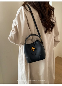Detail of black pebbled leather bucket bag with gold twist lock and adjustable strap