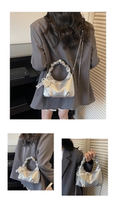 Detailed macro view of silver metallic pleated handbag with pearl heart charm and lace bow