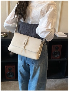 Detail of off-white lychee pattern leather shoulder bag with a metal buckle clasp