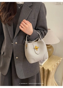 Detail of cream white bucket bag with pebble leather texture and gold twist lock clasp