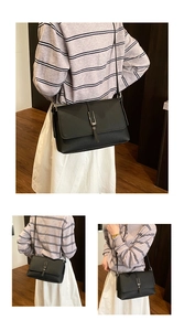 Detail view of black lychee grain leather crossbody bag with metal buckle closure
