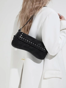 Retro black crescent shoulder bag with silver rivet details worn by model in white blazer
