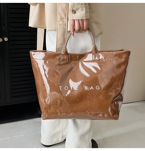 Macro detail of glossy brown tote bag featuring embossed snake skin texture and white text