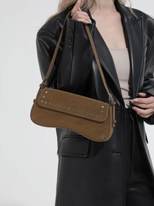 Brown suede underarm bag with silver rivets worn by a model in a black leather jacket