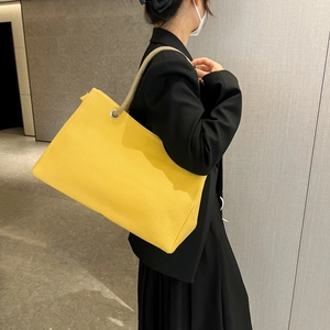 Detail of bright yellow canvas tote bag with beige thick rope handles and silver eyelets