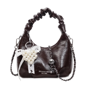 Deep brown glossy crescent handbag with pleated handle and white lace bow pendant charm