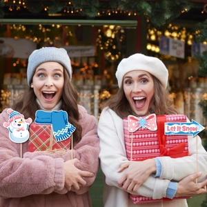 Women using winter party photo booth props with Let It Snow sign and snowman designs