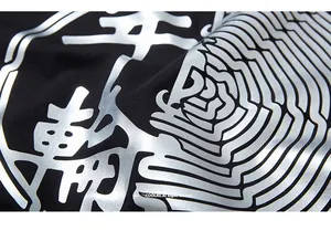 Detailaufnahme des silbernen Metalldrucks auf einem schwarzen Oversize-T-Shirt aus Baumwolle