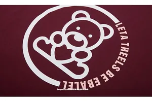 Close-up of a burgundy cotton t-shirt featuring a white cartoon bear with heart print