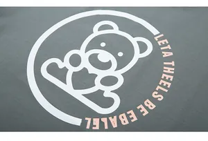 Close-up of white bear outline and pink typography printed on green cotton t-shirt fabric