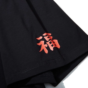 Makro-Detail des schwarzen Oversize-T-Shirts mit rotem Schriftzug-Druck am Ärmelsaum
