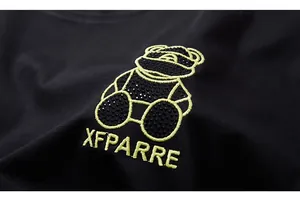 Macro detail of bear embroidery and rhinestones on black cotton t-shirt fabric