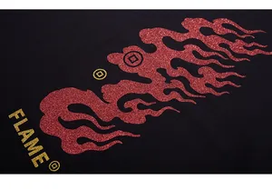 Macro shot of red glitter flame print with gold coins and FLAME text on black fabric