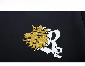Macro detail of golden glitter lion crown print and white lettering on black cotton fabric