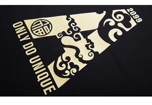 Detail of gold graphic print with Chinese clouds and Only Do Unique text on black T-shirt