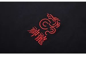 Close-up of red Chinese dragon embroidery and calligraphy on premium black cotton fabric