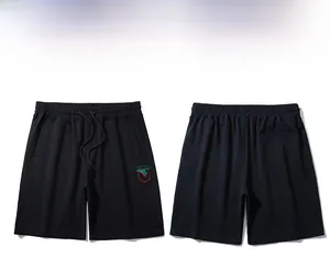 Detail view of black athletic shorts featuring green deer embroidery and drawstring waist