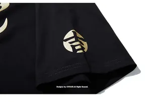 Détail d'un t-shirt noir oversize montrant un logo doré et la texture du tissu en maille