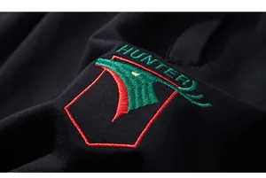 Close-up of intricate red and green Hunter embroidery on black knit athletic shorts