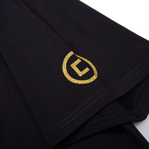 Oversized black cotton T-shirt featuring a detailed golden glitter logo on the sleeve cuff