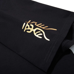 Dettaglio della stampa a dragone dorato su t-shirt nera oversize in tessuto pregiato