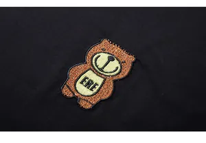 Detail of cartoon bear patch with brown rhinestones and ERE embroidery on black T-shirt