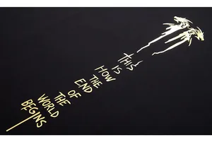 Macro view of gold dragon print and text detail on a black cotton oversized T-shirt