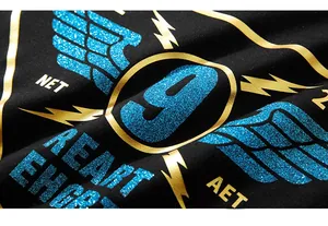 Detail of blue glitter 9 wings and gold metallic print on black cotton oversize T-shirt