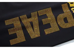 Detail der goldenen PEACE-Strass-Verzierung auf schwarzer Herren-Sporthose