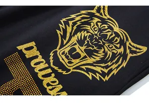 Detailaufnahme des goldenen Glitzer-Tigerkopf-Drucks auf schwarzer Jogginghose